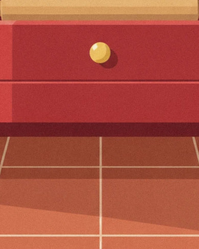 Le tiroir rouge à bouton doré du buffet de cuisine, au-dessus du carrelage terracotta