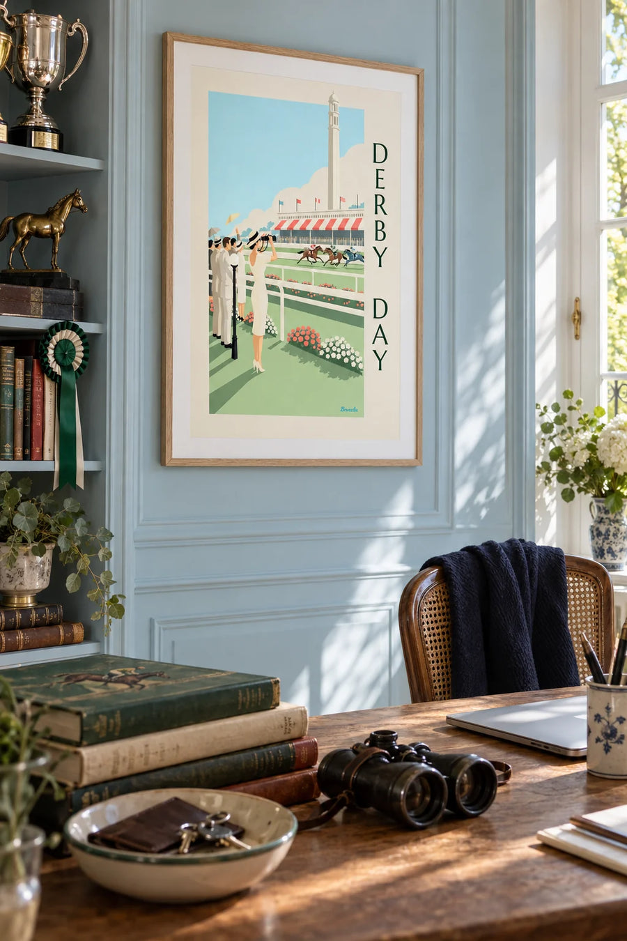 Poster of a woman in a big hat at a racetrack: framed on the wall