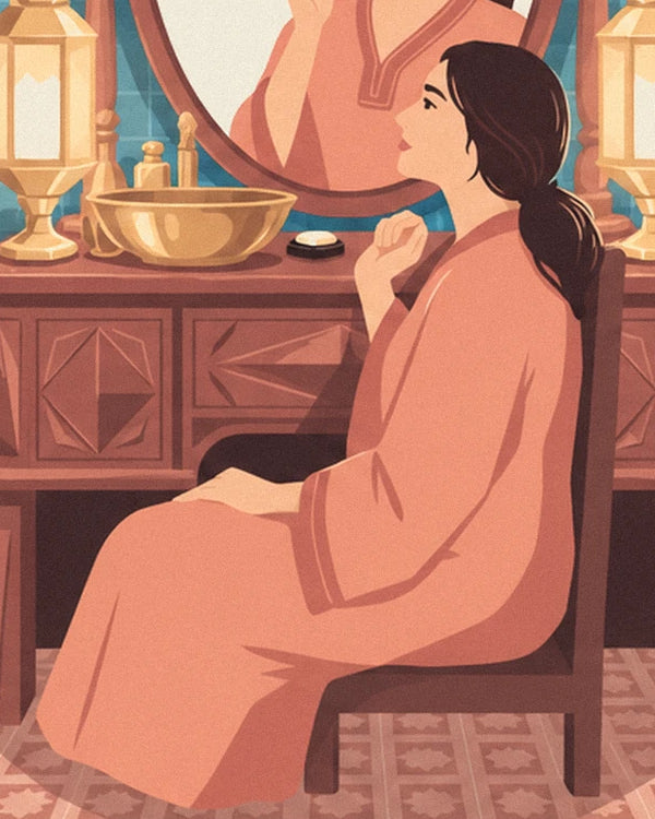 The woman in a coral dress seated at her wooden dressing table with its golden basin